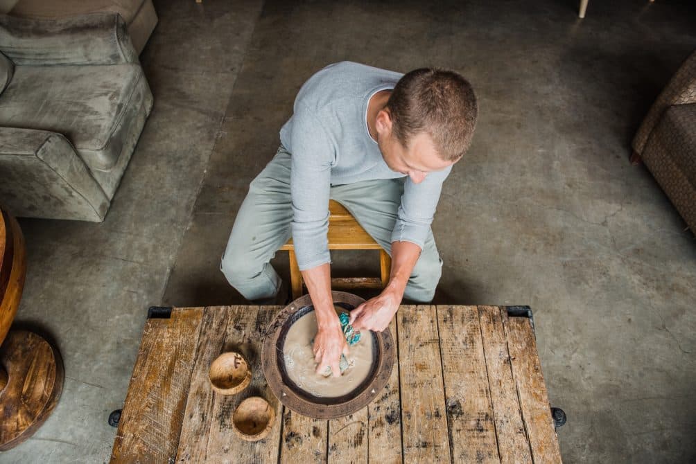 A kavatender hand-kneading and straining kava root in a wooden bowl at Bula Kava House