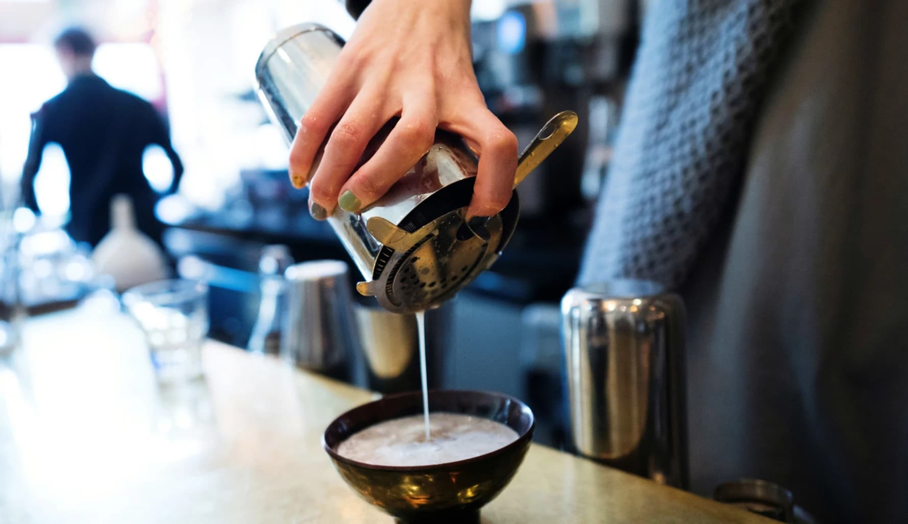 A McKinney Leaf Café barista straining a freshly mixed kava café drink into a bowl
