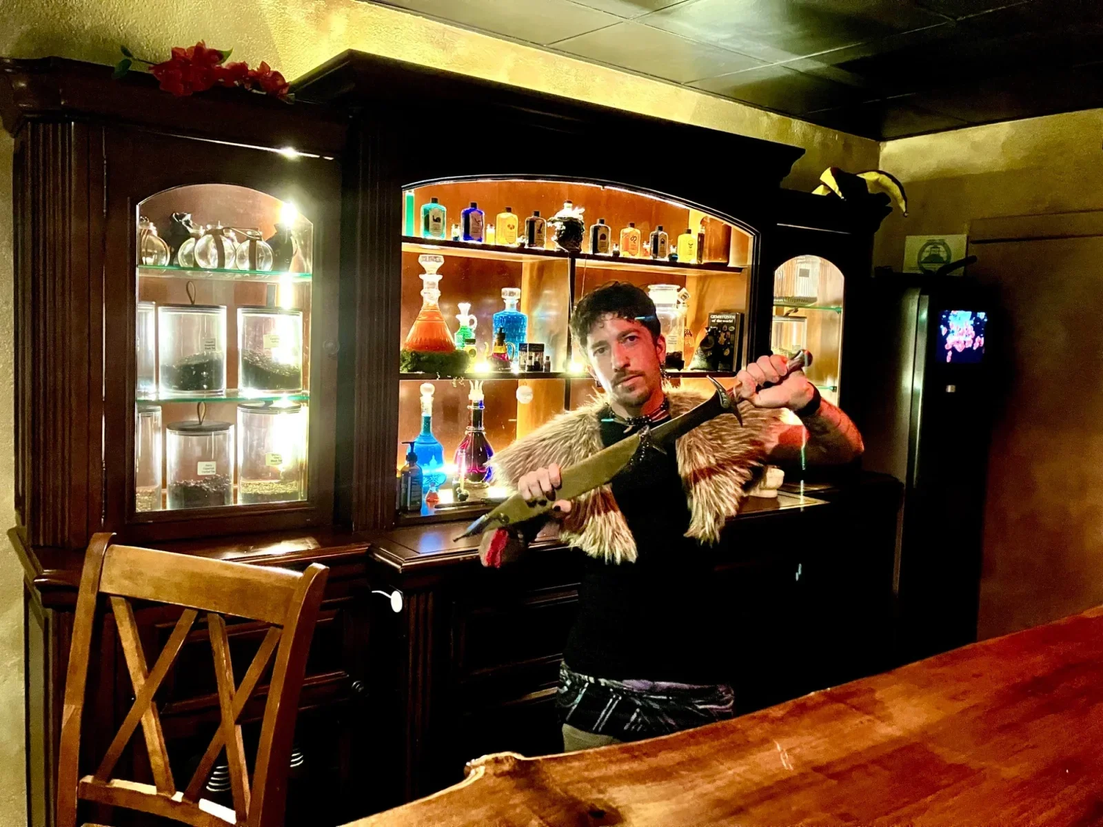 A staff member behind Moon and Root’s wooden bar with illuminated bottles
