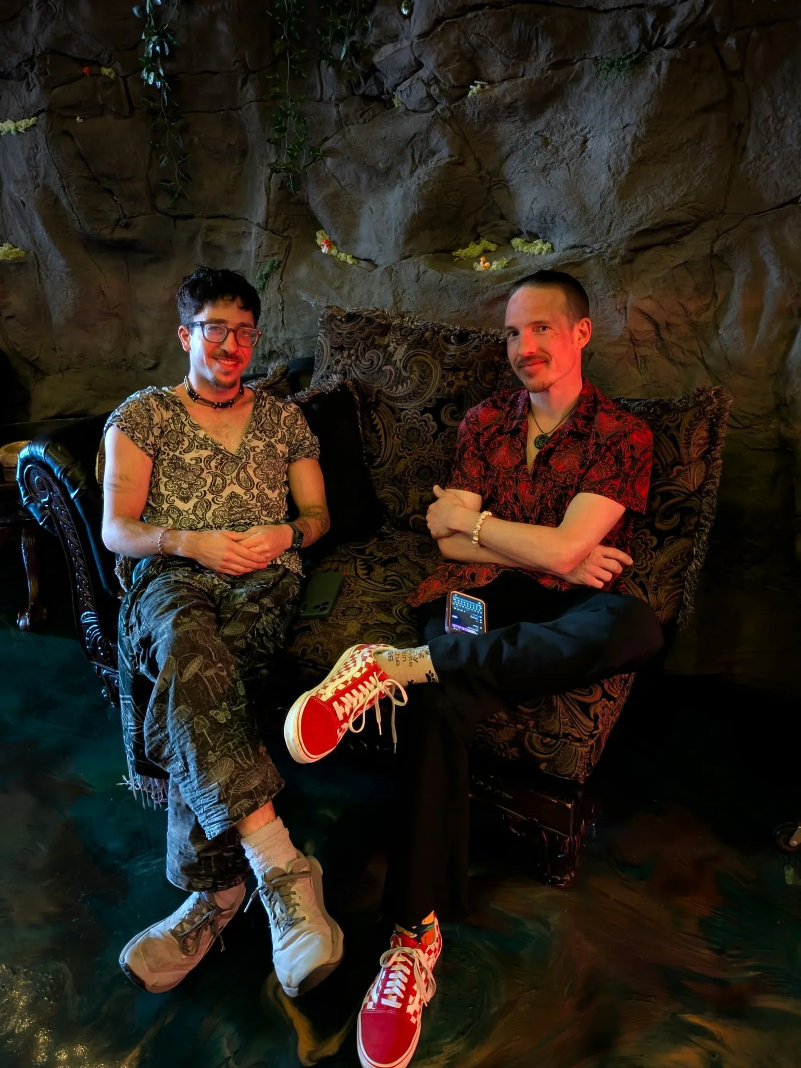 Two guests relaxing in armchairs against Moon and Root’s textured stone-style wall