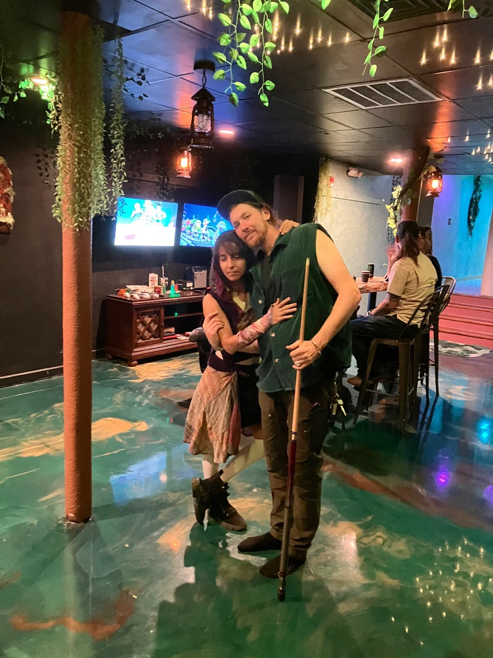 Guests holding pool cues inside Moon and Root’s plant-filled lounge