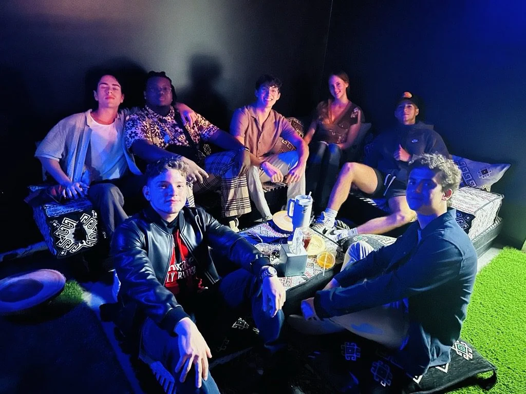 Seven people sit together around a low table on Tribe Tea Lounge’s patterned floor cushions
