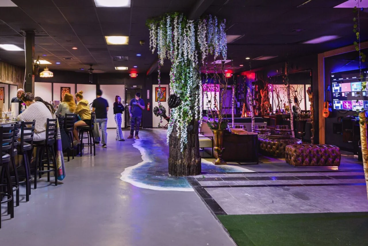 People sit at Tribe Tea Lounge’s counter beside floral columns, lounge seating, and its painted floor