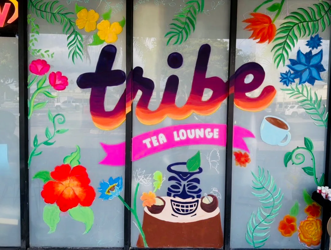 Tribe Tea Lounge’s colorful window mural features flowers, tropical leaves, and its name