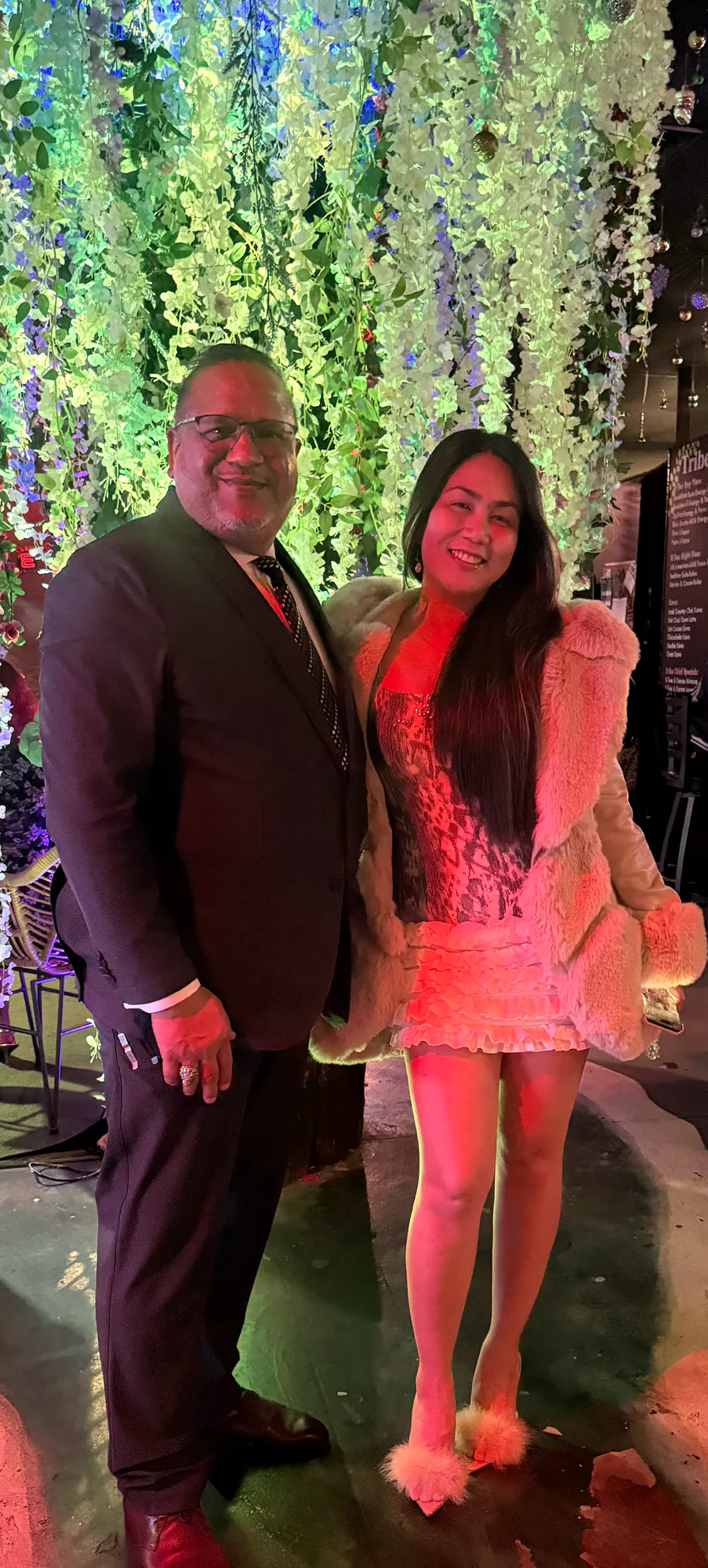 Tribe founders Tariq and Rose stand together beneath the lounge’s hanging flowers