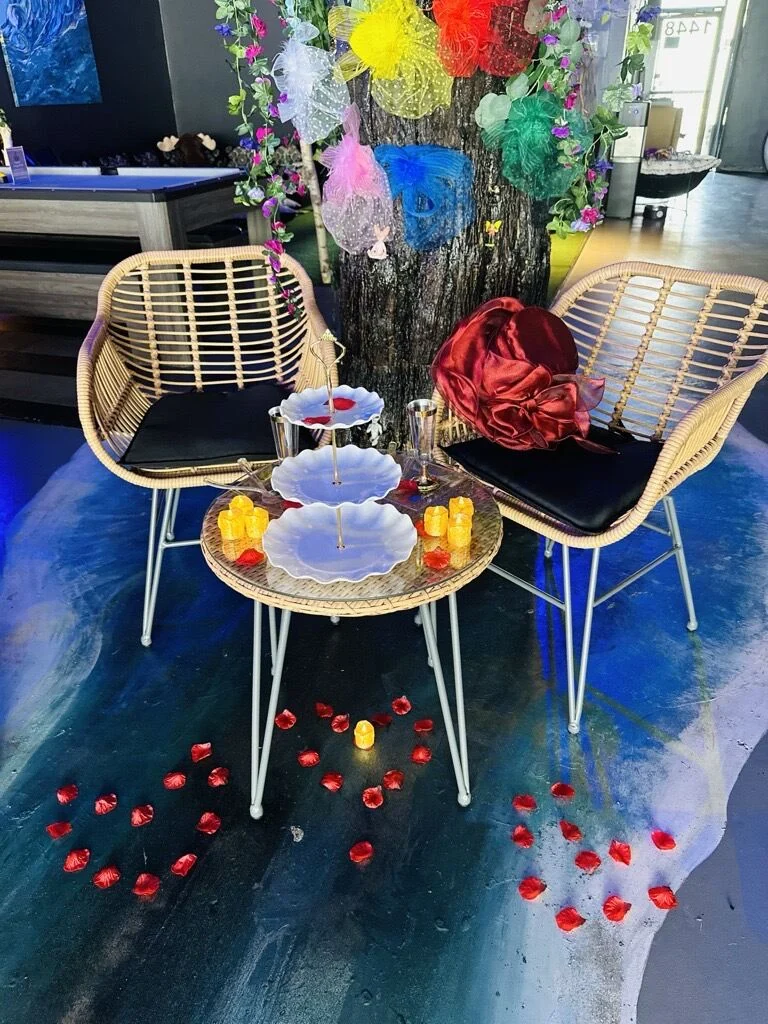 A small table for two at Tribe is arranged with tiered plates, flowers, and glowing candles