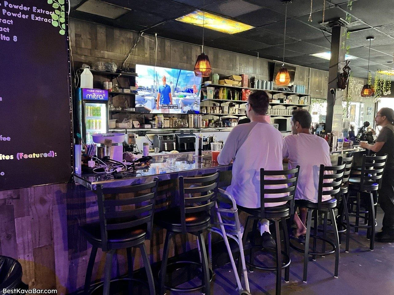 People sit at Tribe Tea Lounge’s counter beneath pendant lights, facing the drink-preparation area