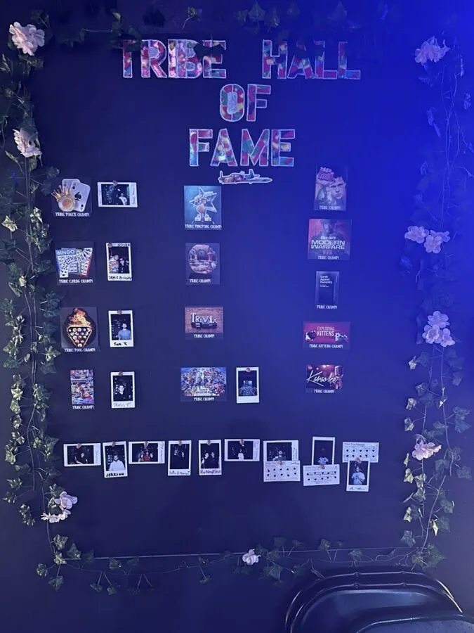 Tribe Tea Lounge’s Hall of Fame displays game-champion cards and small photographs on a flower-framed wall